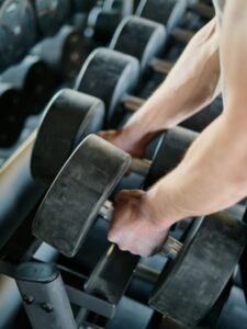 A person pulling dumbbells off of a rack.